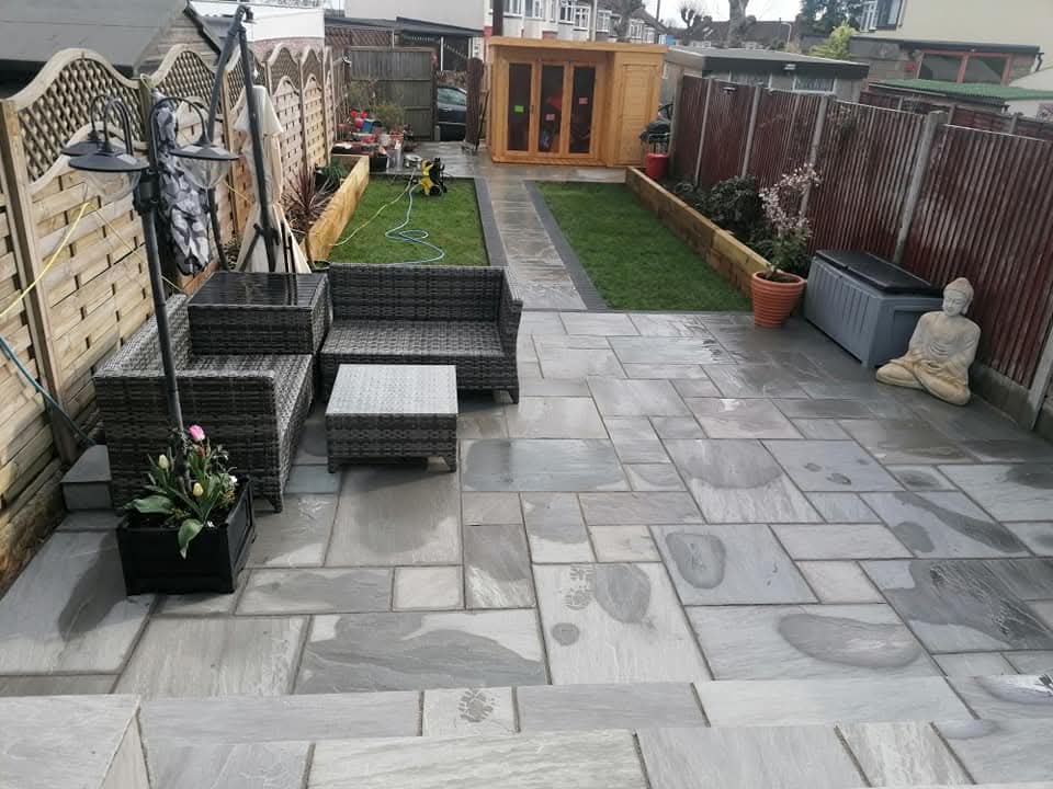 Grey sandstone patio with raised sleeper beds and a strip of lawn, built by Golden Hands