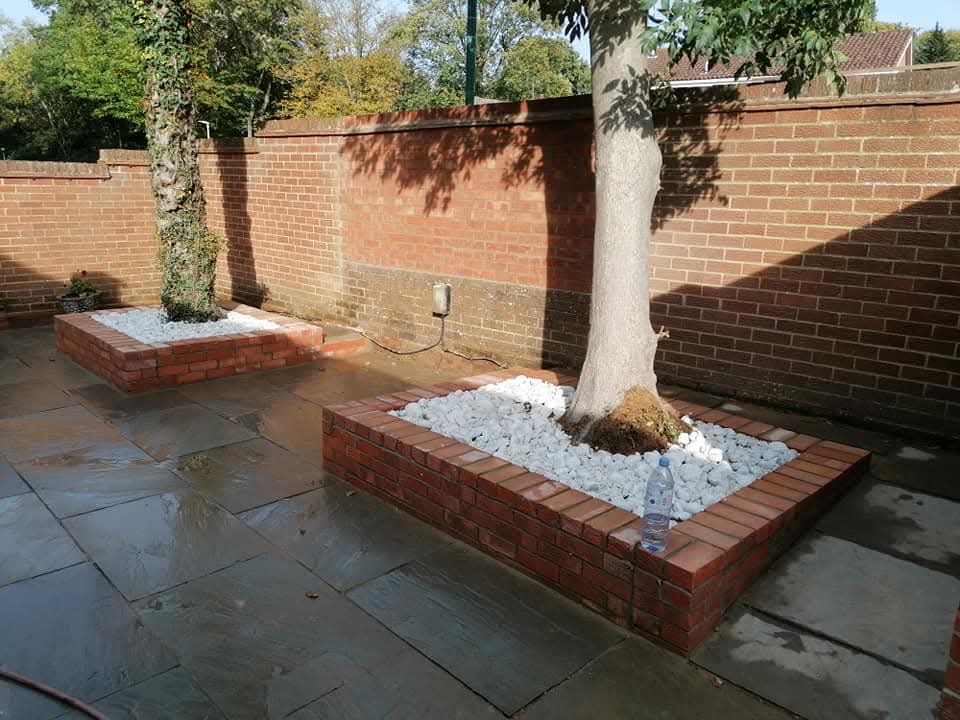 Brick tree planters filled with white stone set into sandstone paving