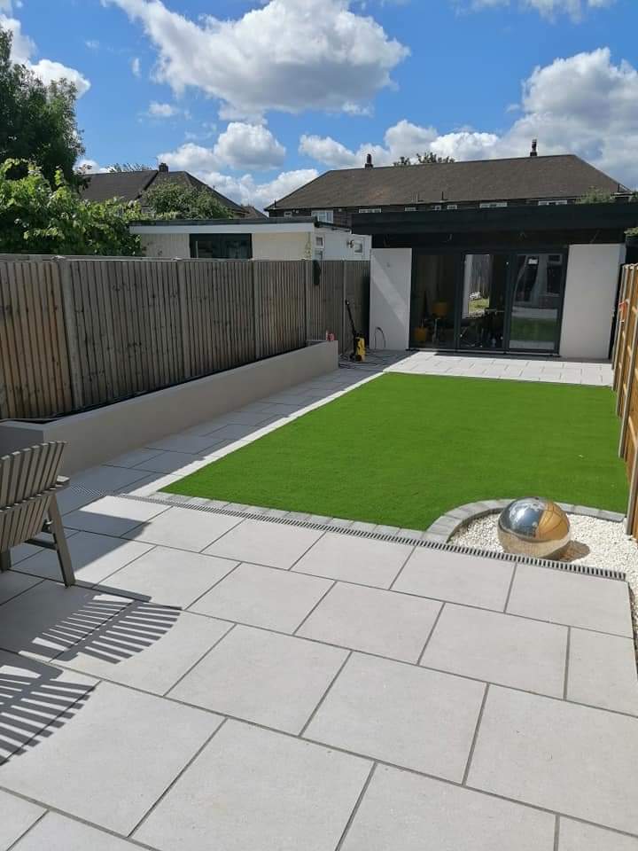 Garden room with porcelain paving, artificial lawn and a water feature